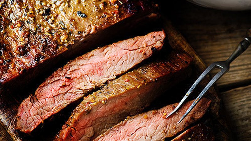 Sliced glazed beef roast on a wooden board